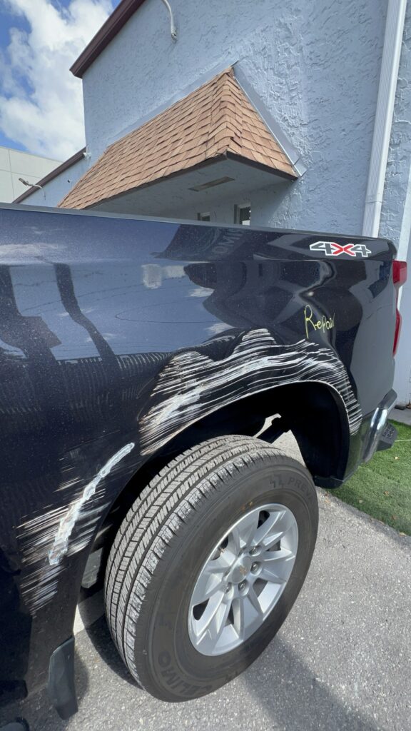 Vehicle with collision damage showing bent aluminum and metal panels before repair